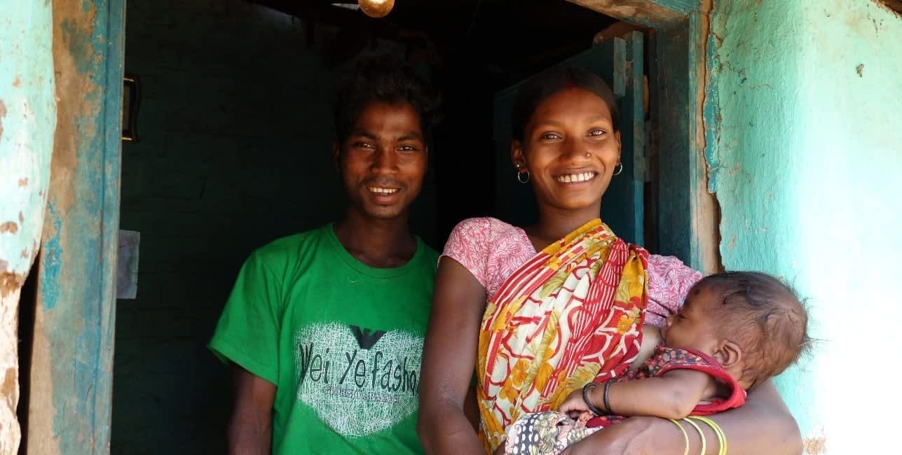 Young couple next to each other. Woman carrying a baby