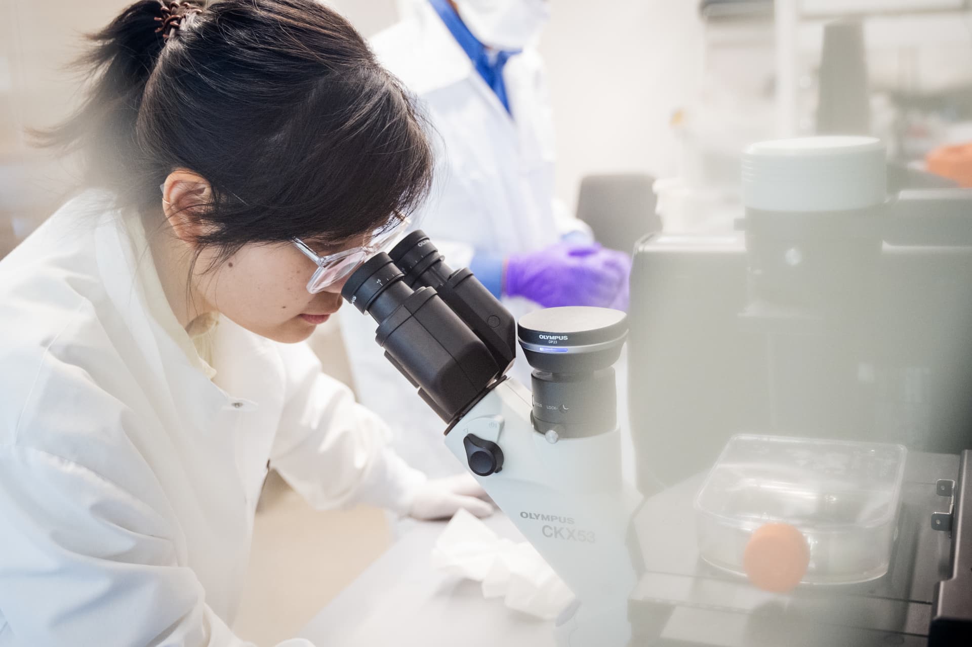 woman looking through microscope