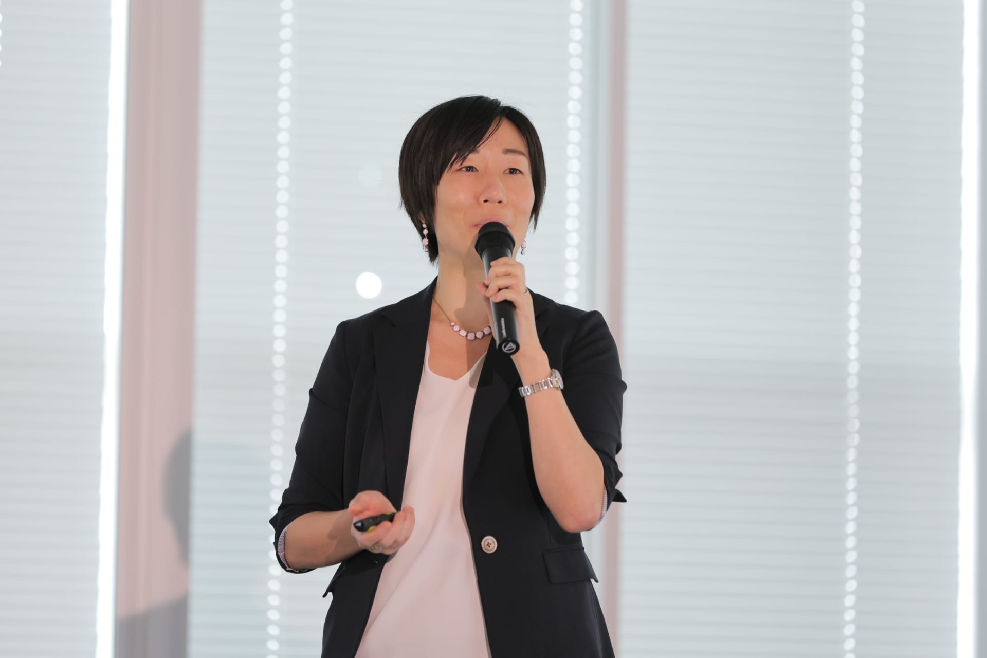 室内でマイクを持ちながらプレゼンテーションを行っている中西さん