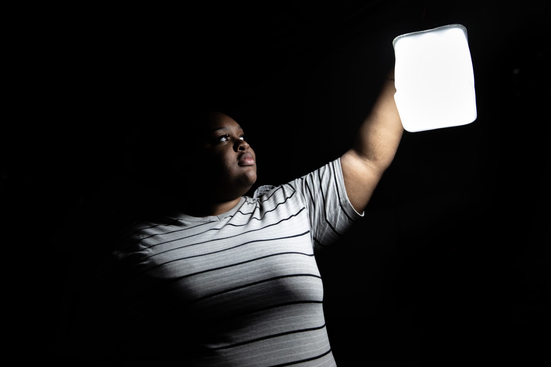 A person holding up a white sign in a dark room.