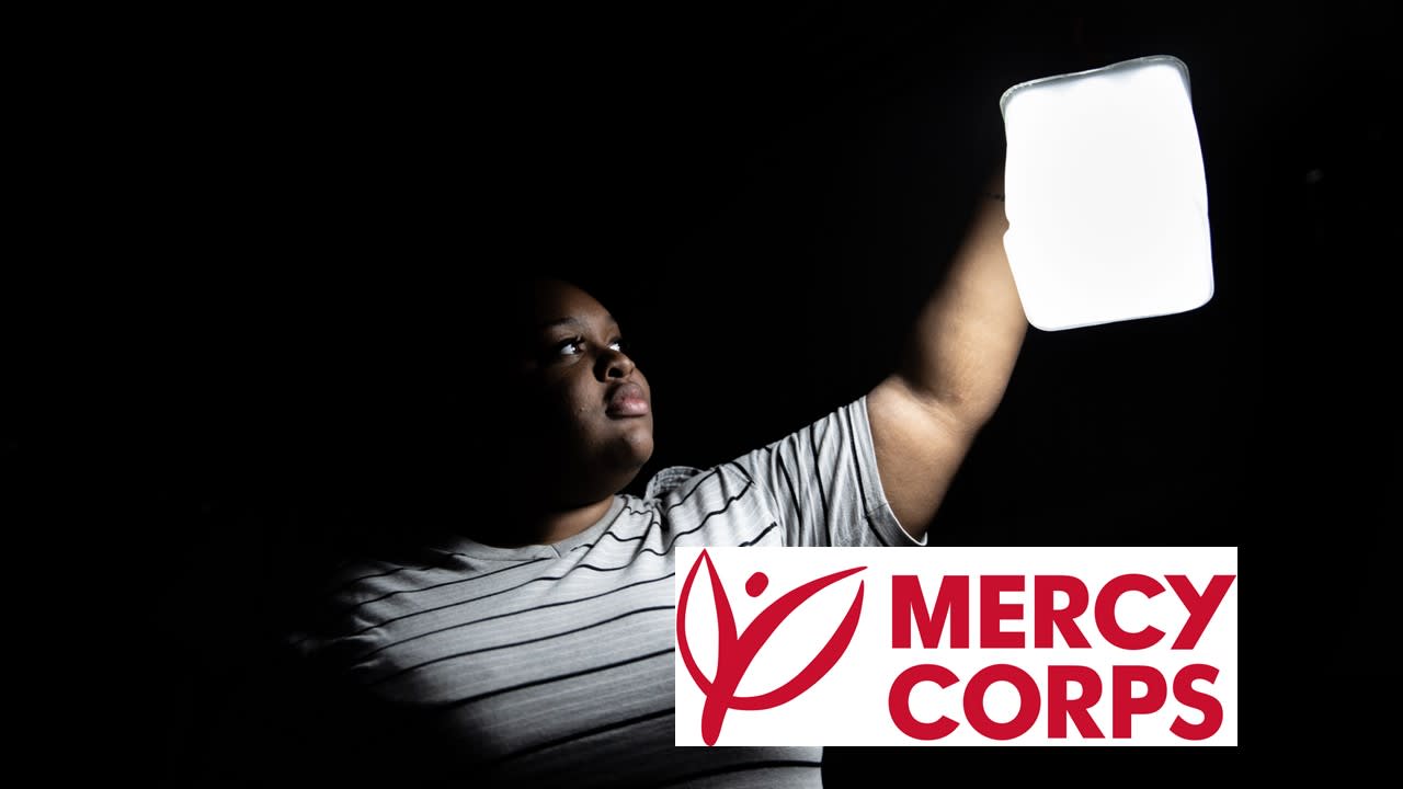 A person holding up a white sign in a dark room.