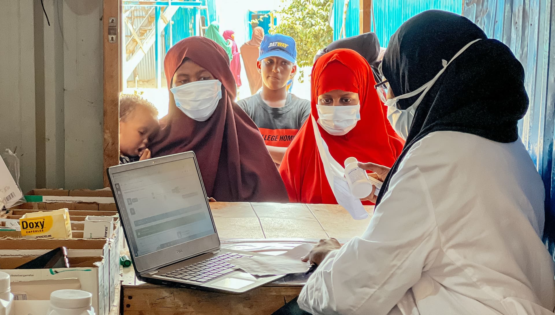 Healthcare workers using digital tools to manage medical supplies and patient-related data at a health facility.