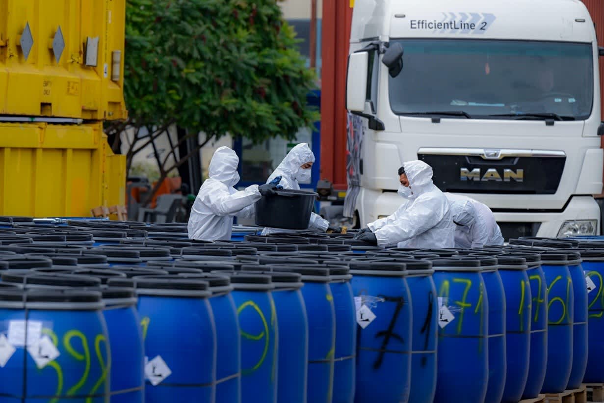 Trained workers handling medical waste containers using protective equipment as part of a safe healthcare waste management process.