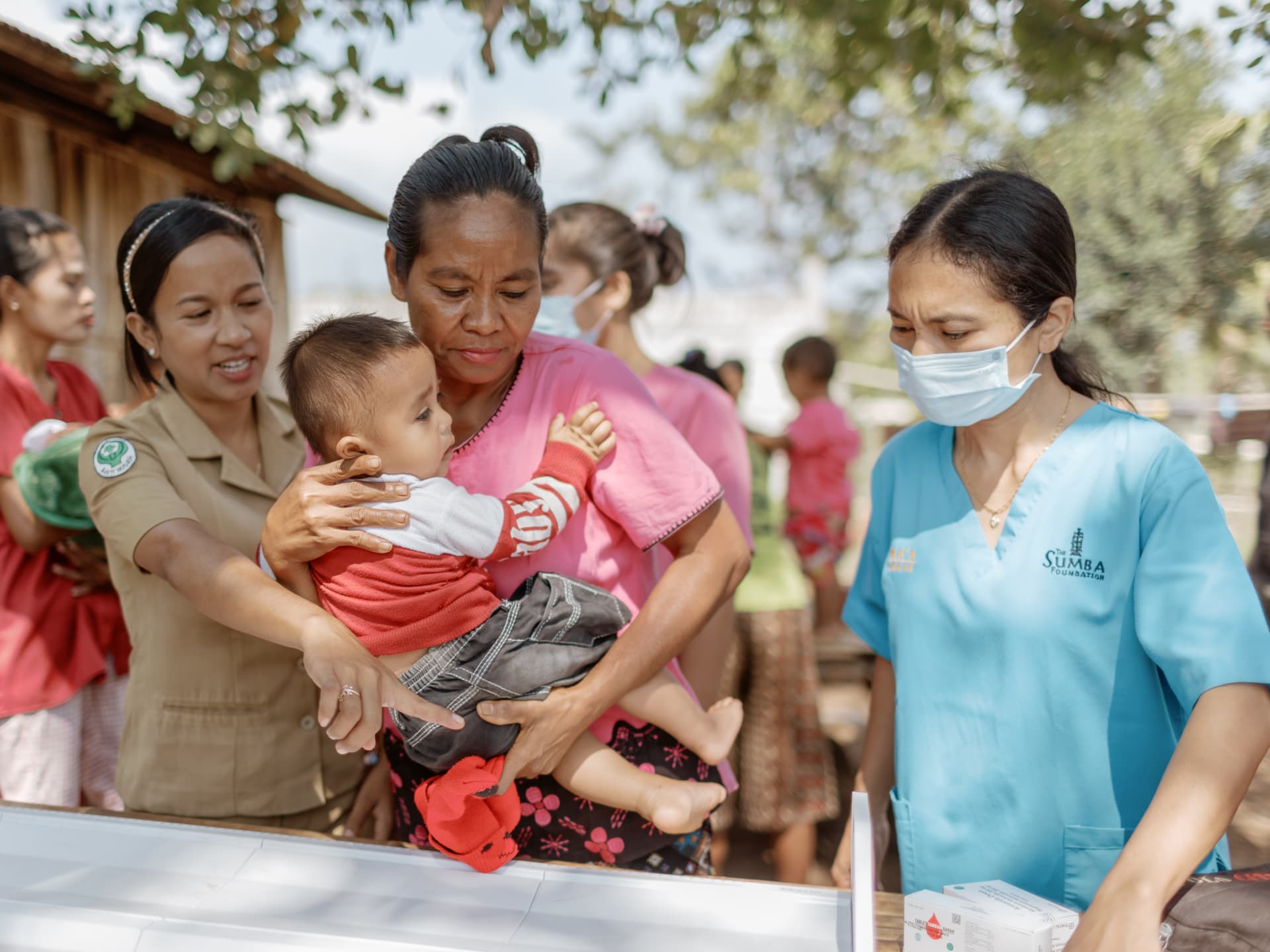 Community health workers providing nutritional support to mothers and young children as part of a maternal and child health program in Indonesia.