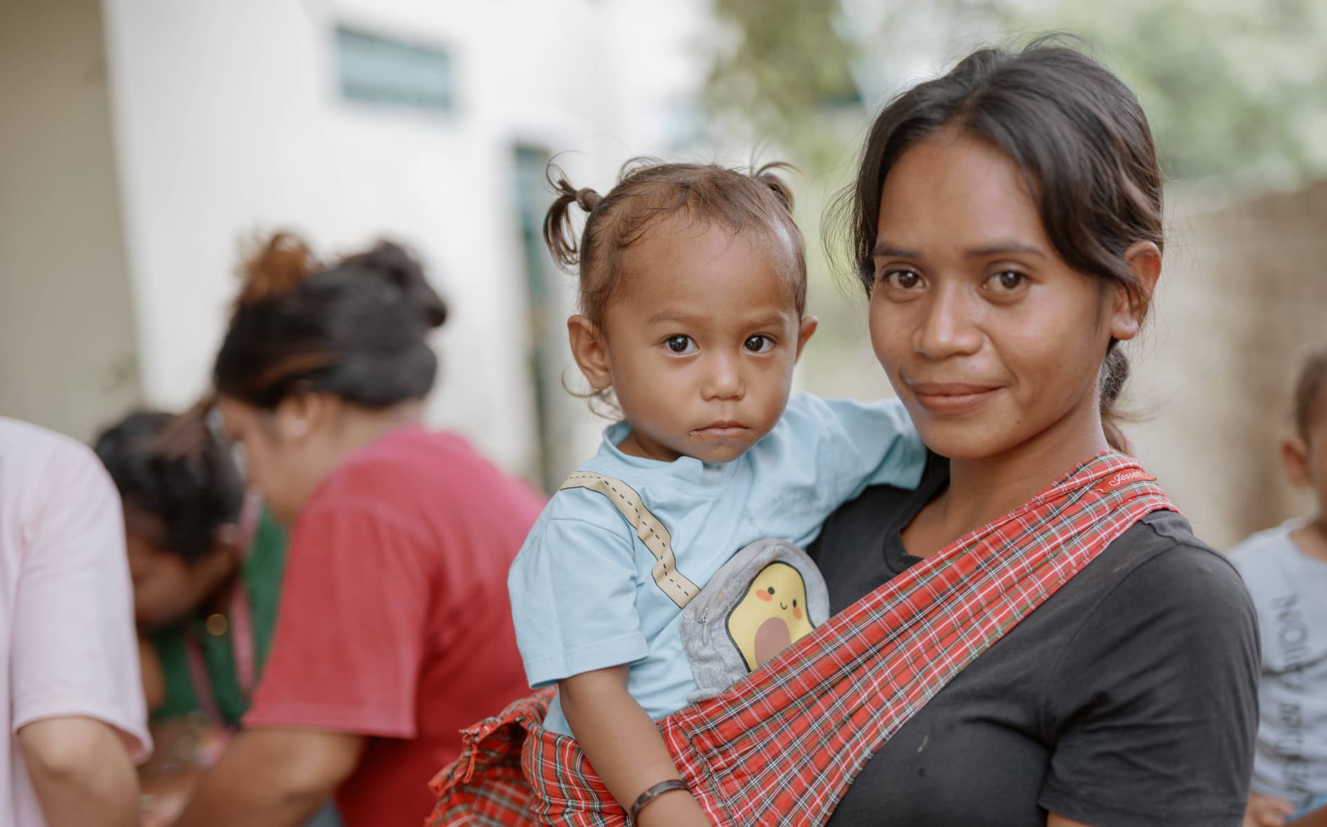 A mother holding a young child while receiving nutrition-related support at a community health setting.