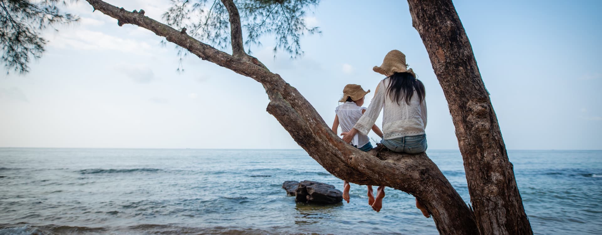 Mother and girl sitting on a tree branch