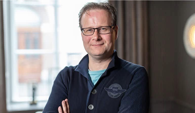 A person wearing glasses and a blue sweater