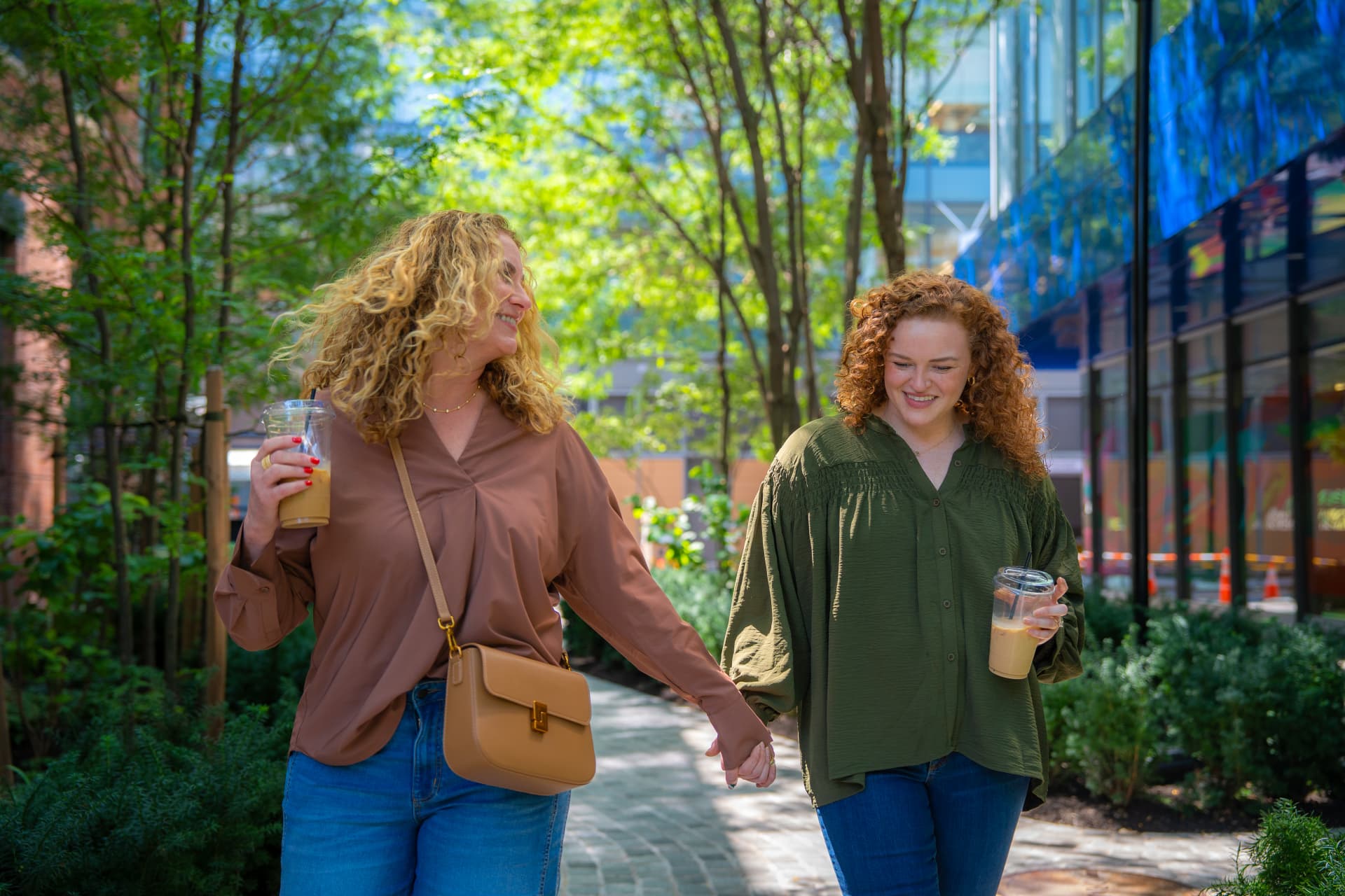 Photograph of two people walking hand in hand outdoors along a tree-lined pathway