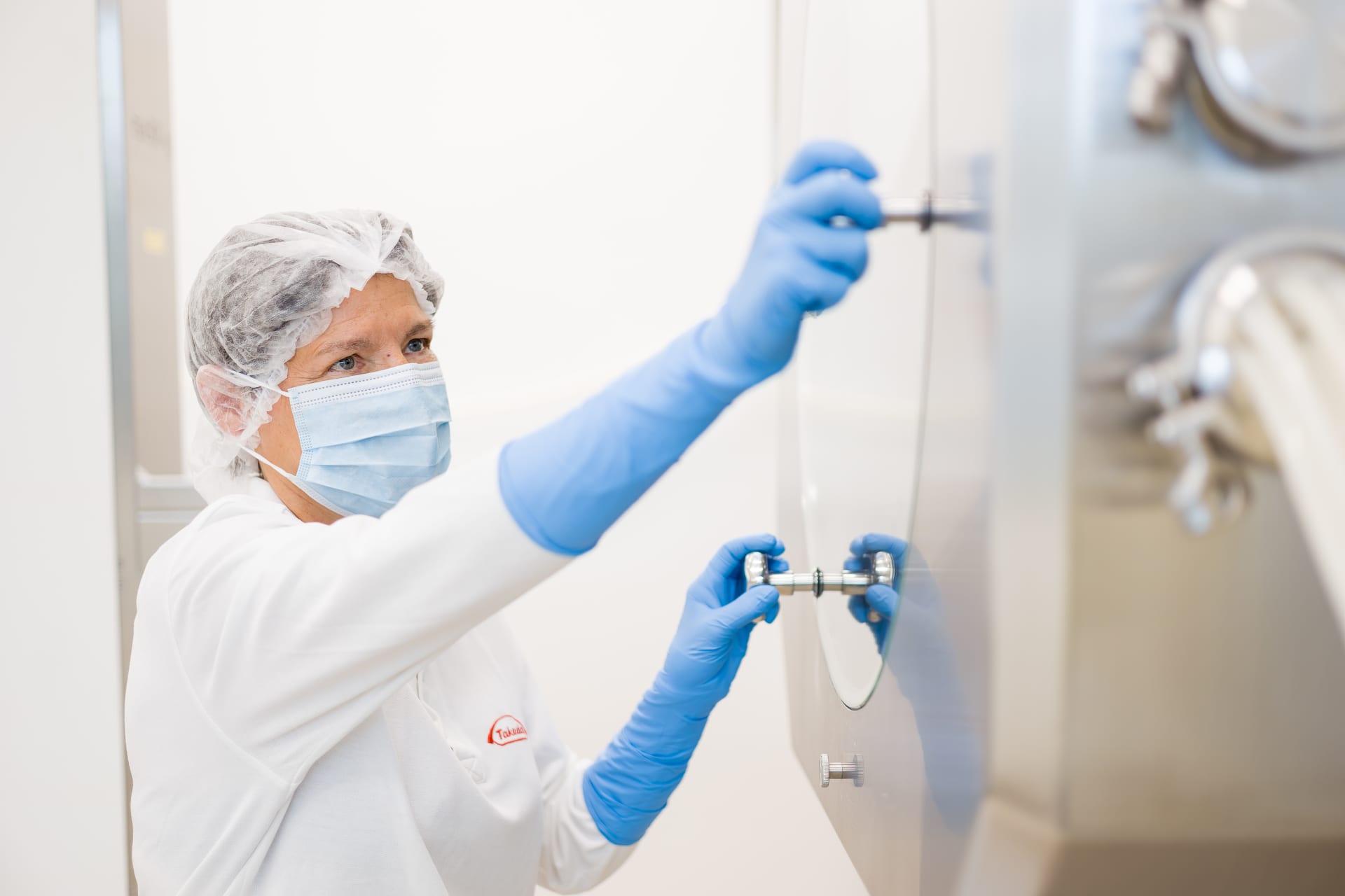 Employee in protective gear operating equipment in a cleanroom