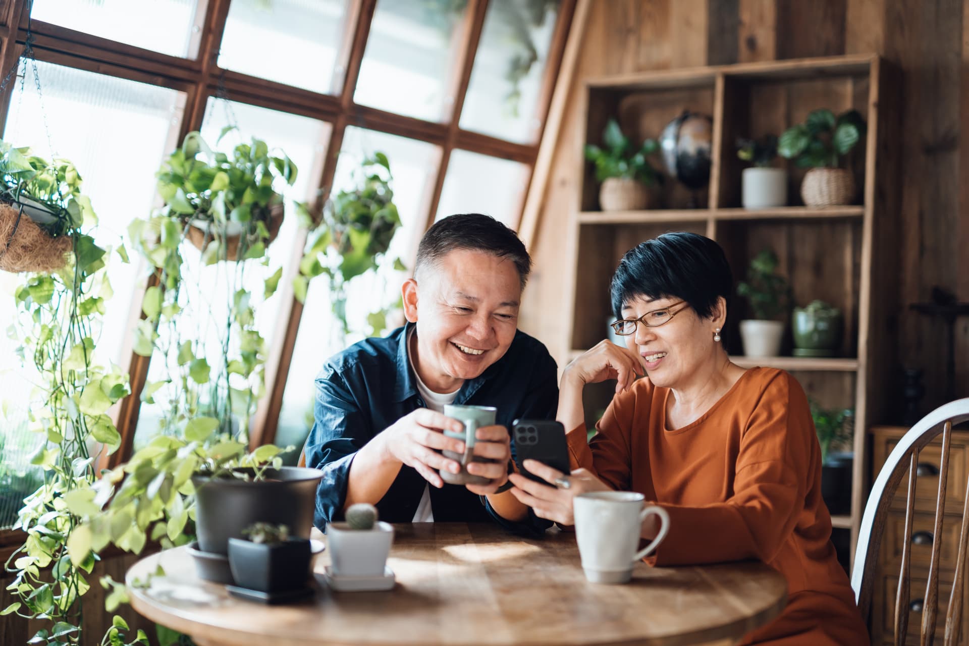 A couple enjoying drinks together while looking at a smartphone screen and chatting.