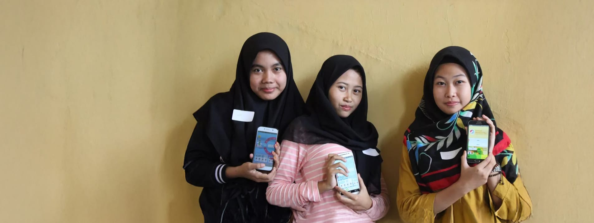 Three girls holding smartphones