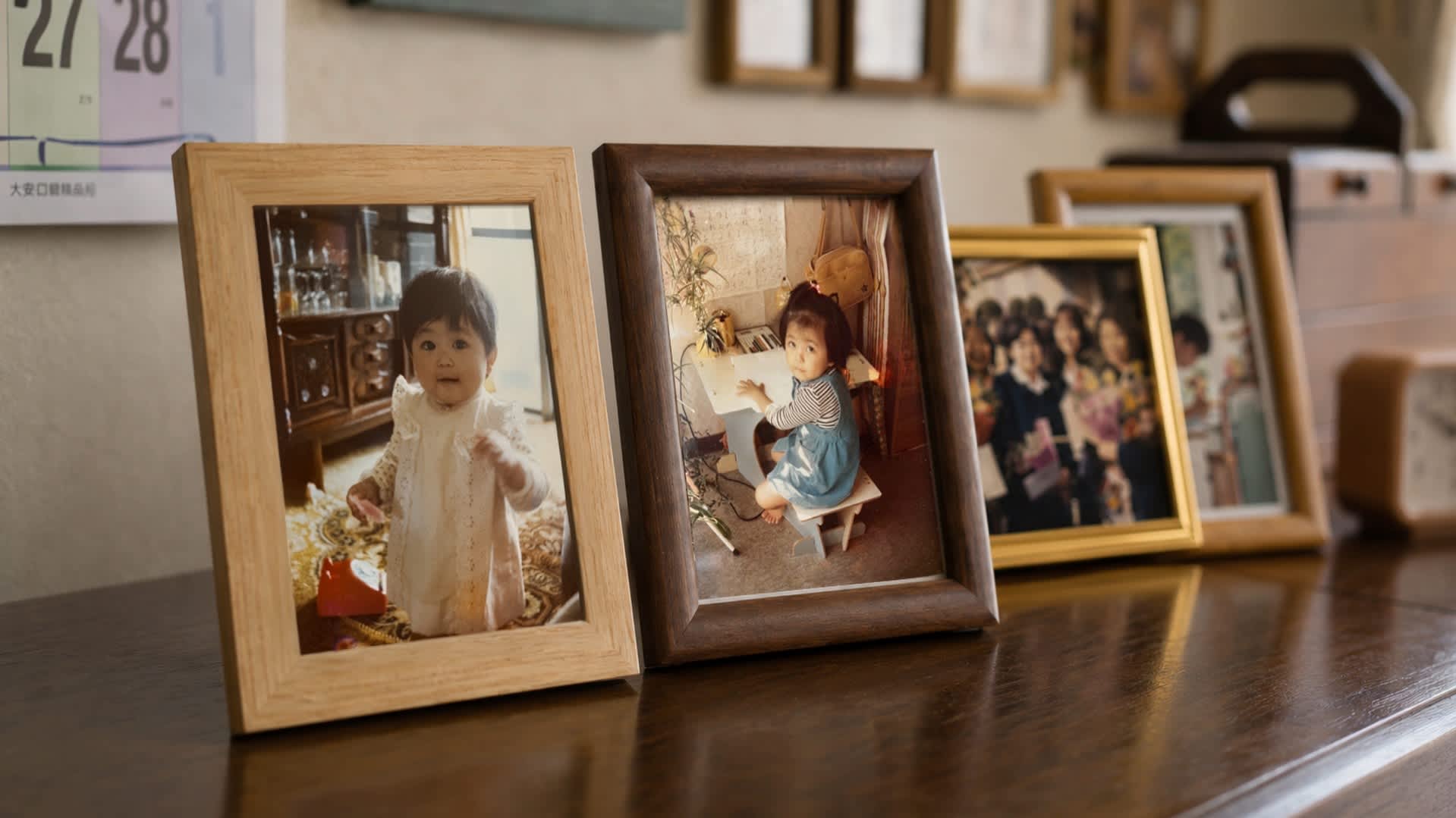 Framed childhood photographs displayed on a wooden table