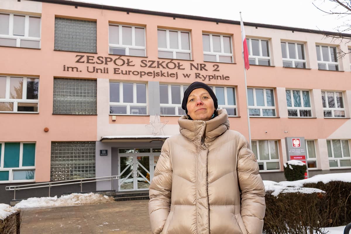 Photograph of a person standing in front of a three-story school building