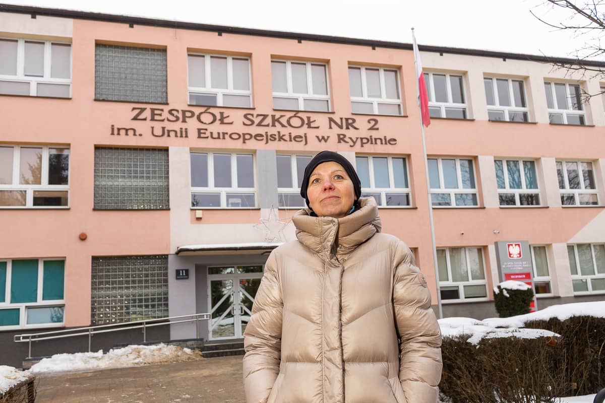 Photograph of a person standing in front of a three-story school building