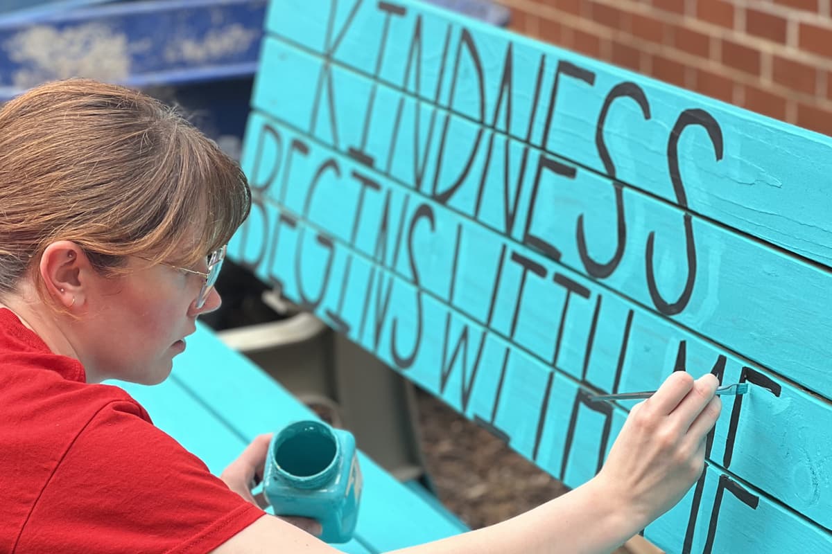 Woman writing on bench "Kindness begins with me"