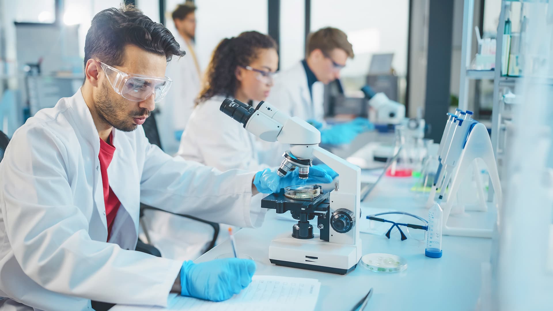 A group of people in lab coats looking through microscopes