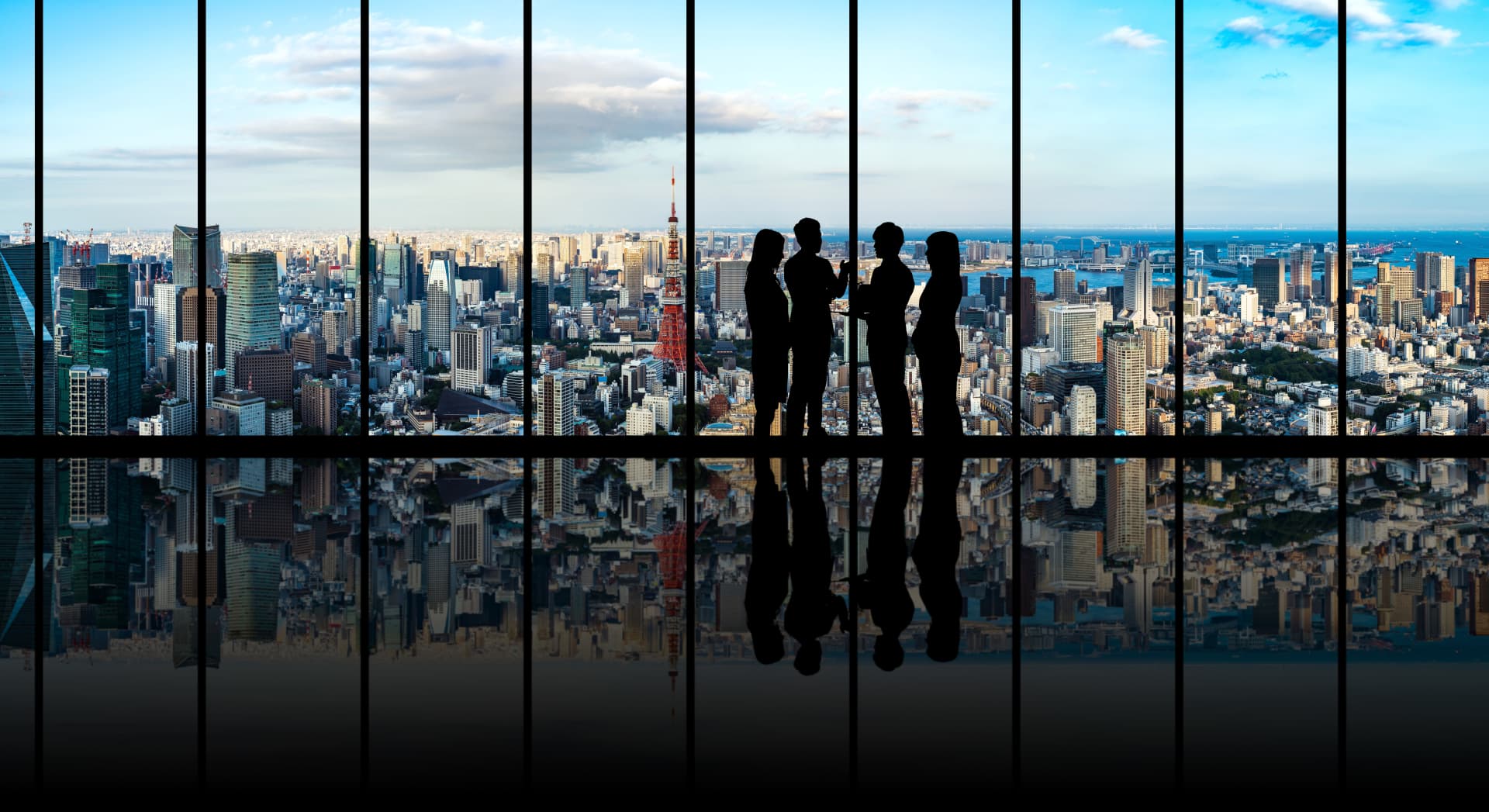 4 people standing in front of a window with a city skyline view