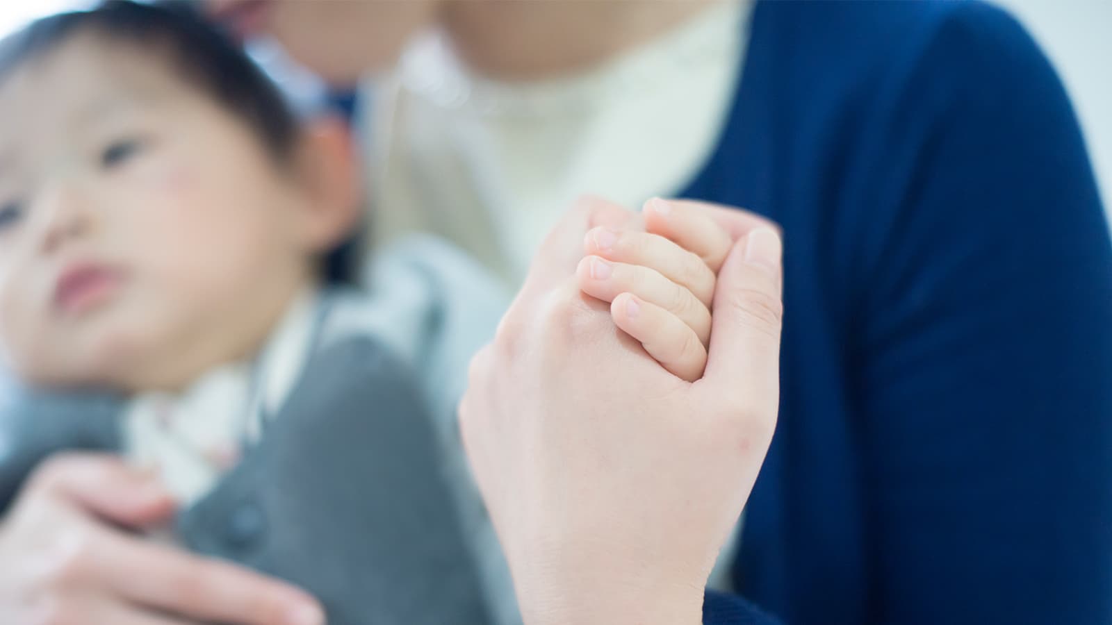 母が赤ちゃんの手を握っている