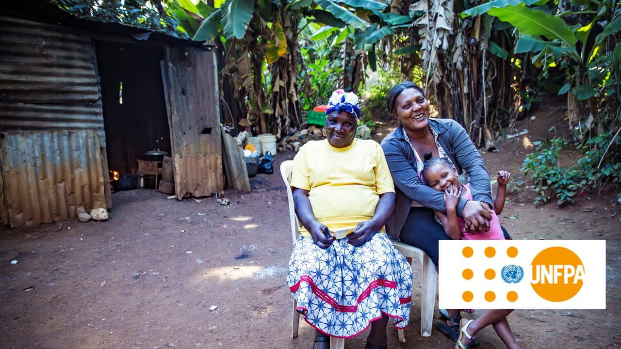 Two women sitting on chairs and one is holding a child