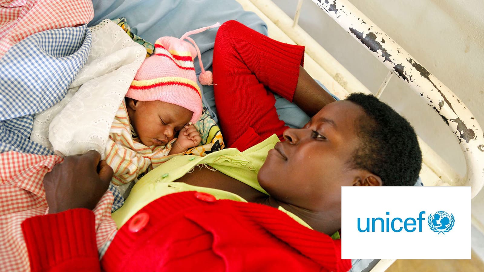 Young man lying in bed next to sleeping baby