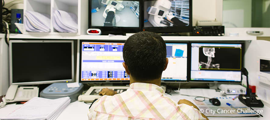 Man sitting in front of four computers, reviewing results provided by scan