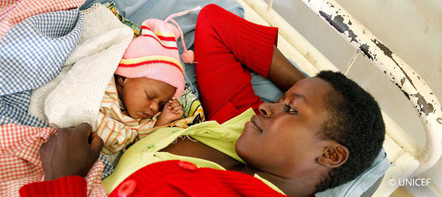 Young man lying in bed next to sleeping baby