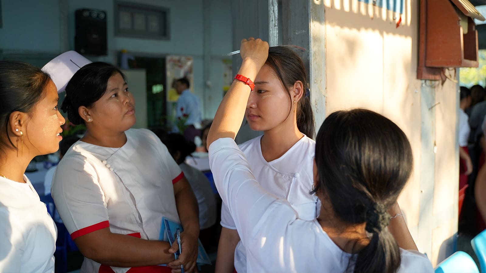 a nurse is measuring how tall a girl is while two more people are watching