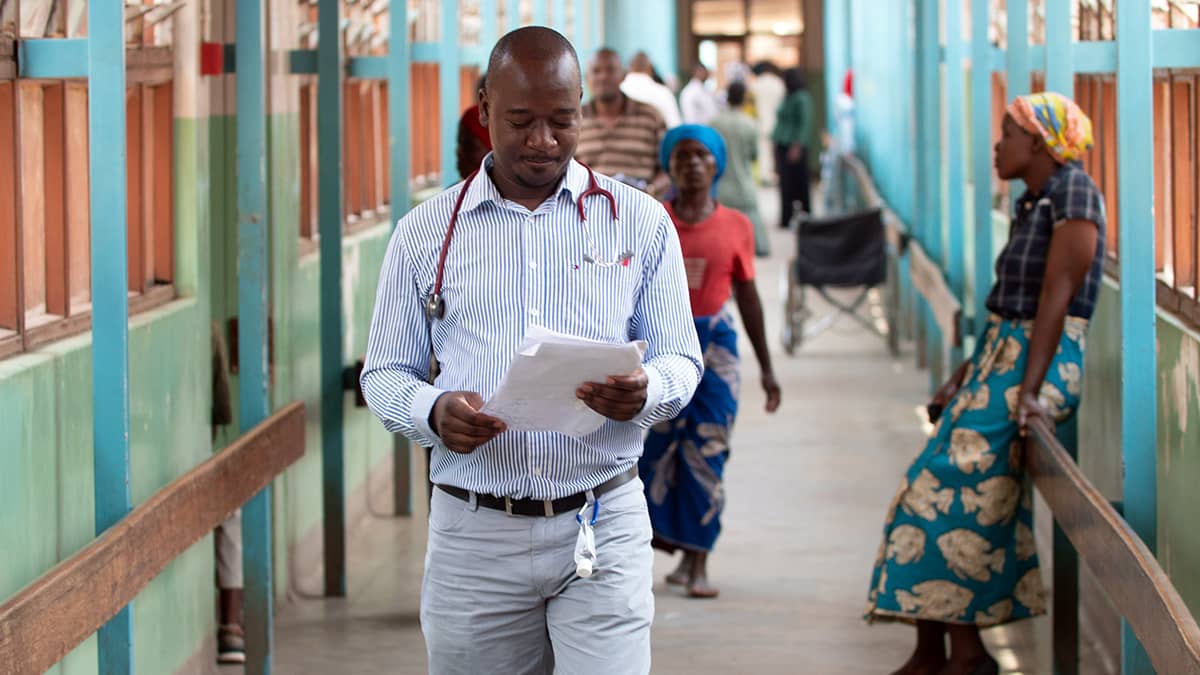 Physician walking in aisle reading a document