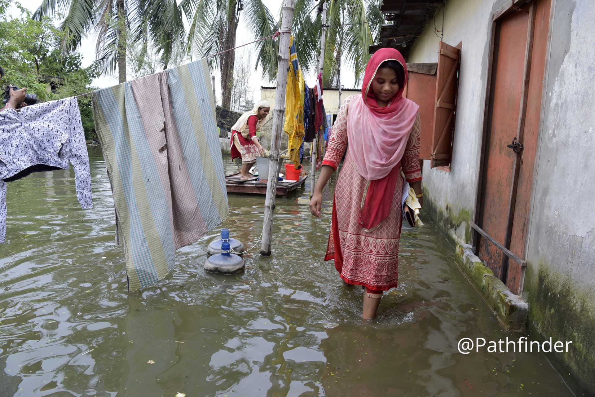 6 Bangladeshi people cross flooded street at DND dam