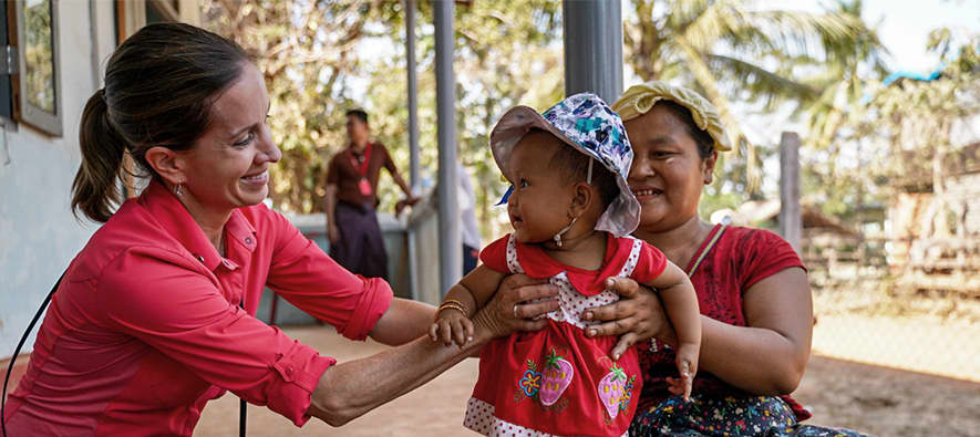 Two women holding a child and smile