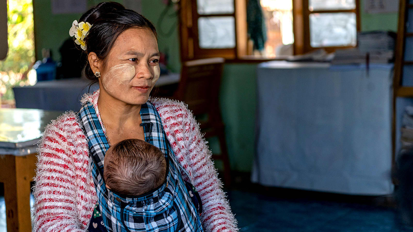 Woman sitting and carrying a baby in a baby sling