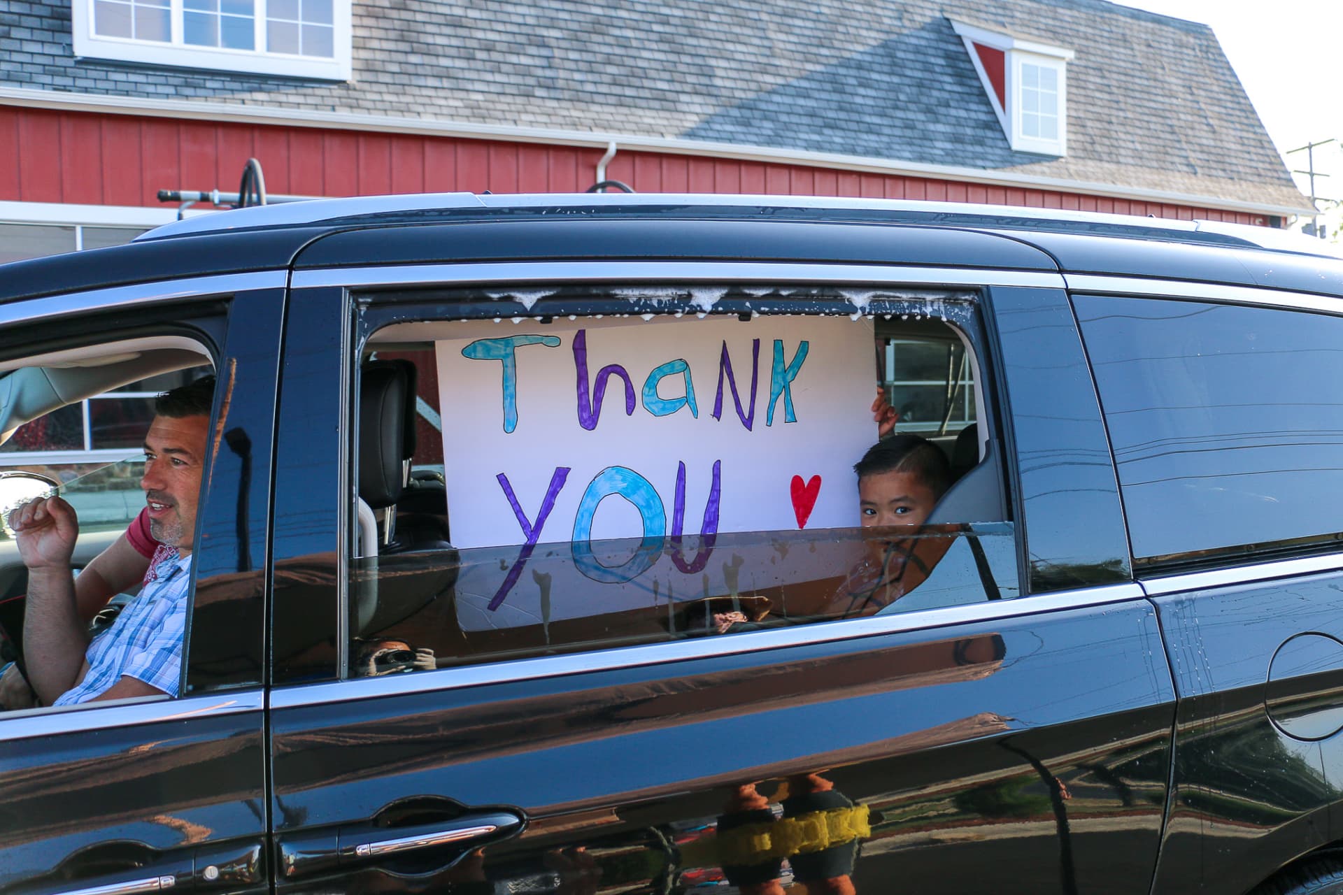 Family in van with Thank you cardboard