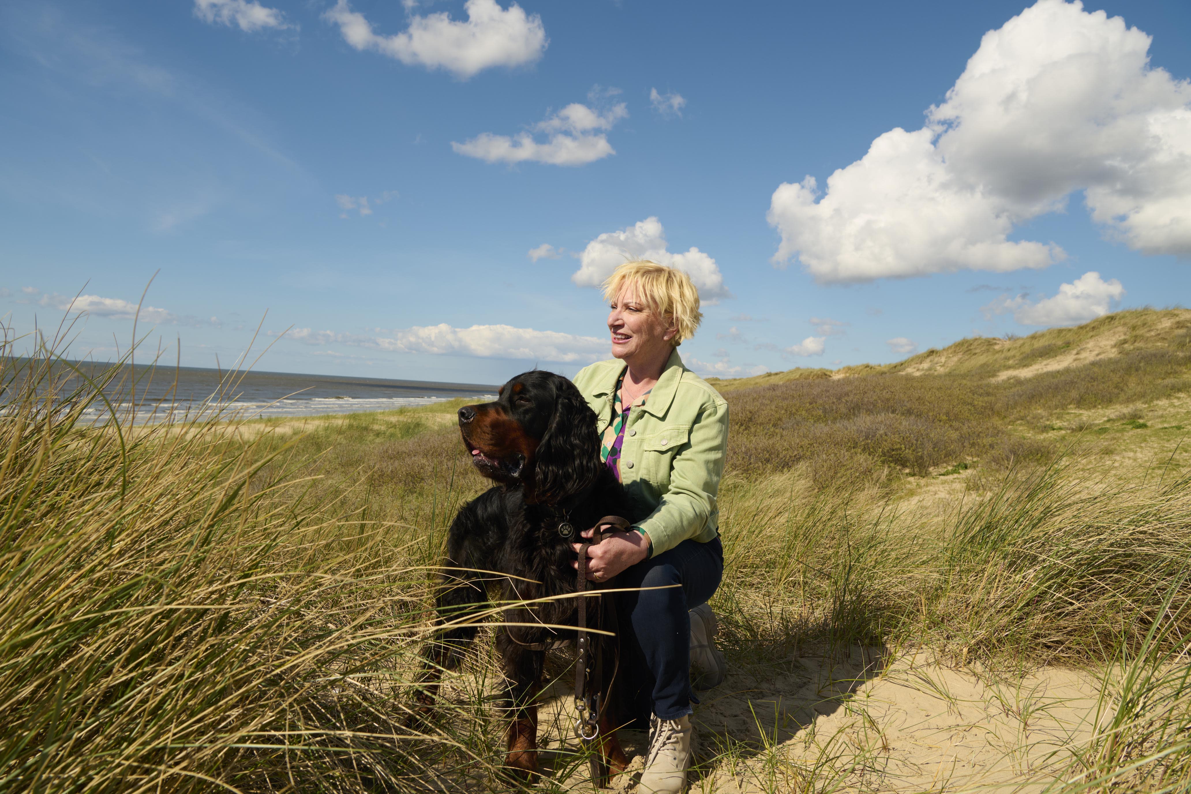 A person and a dog sitting on a grassy field