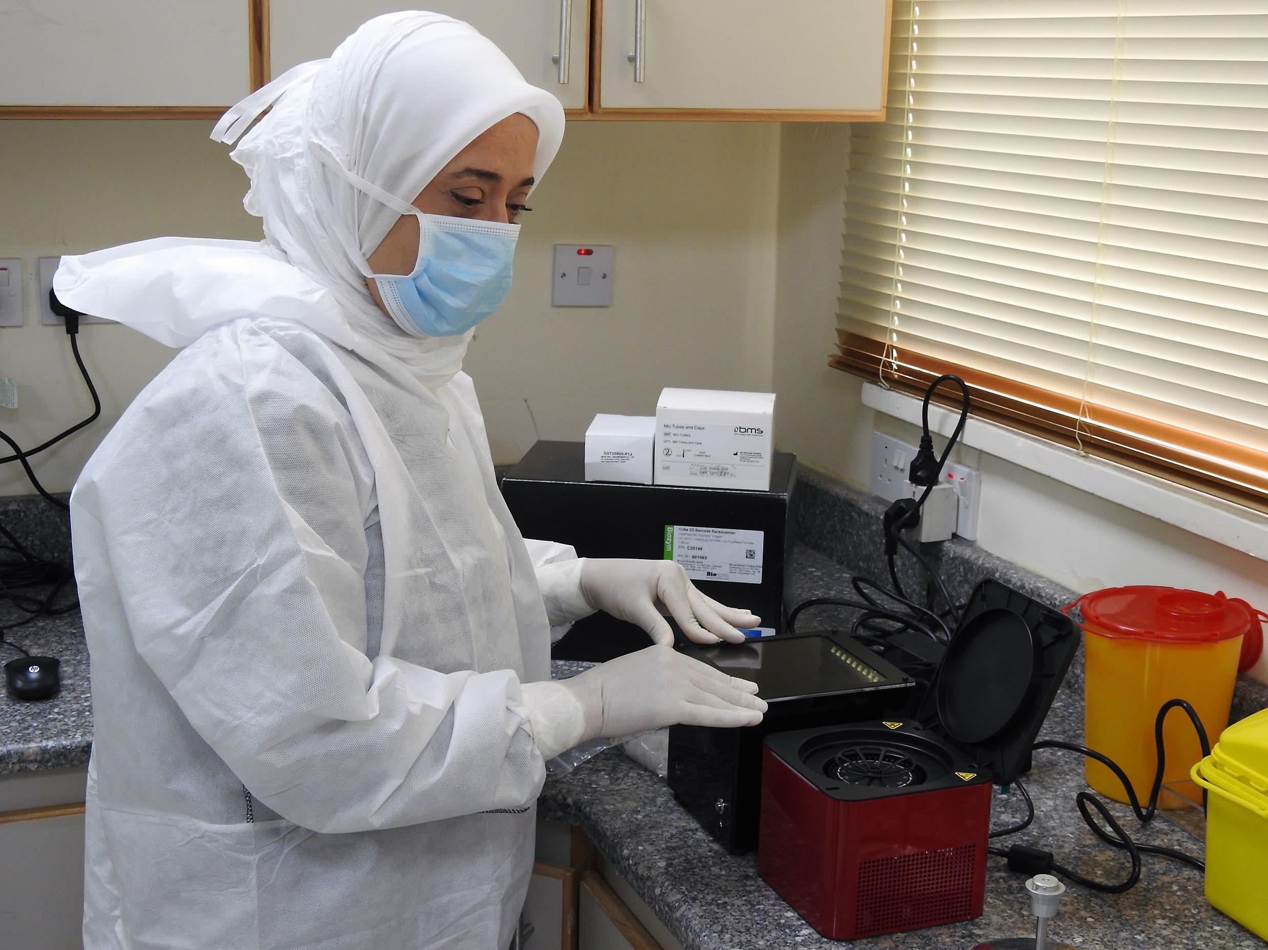 woman with mask and in a lab overall