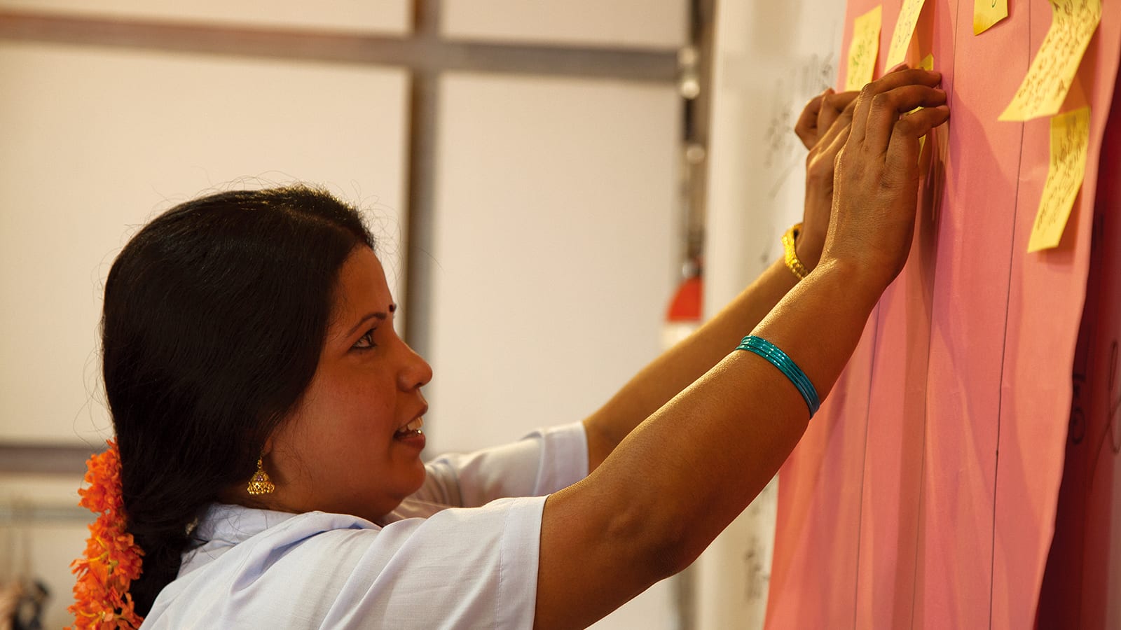 woman pasting sticky note to cardboard on chalkboard