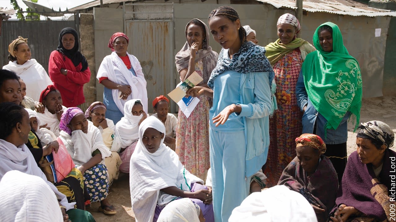 a group of women surround another women which is talking