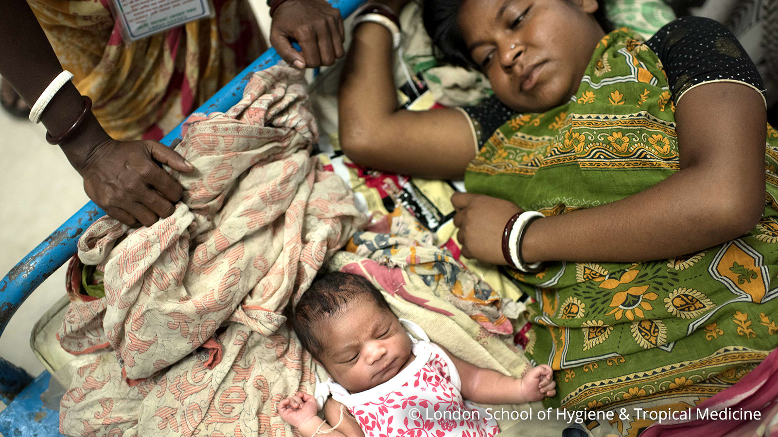 young woman laying in hospital bed with newborn on her side