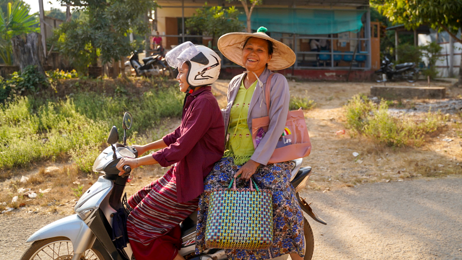 two women sitting on a motor scooter and smile