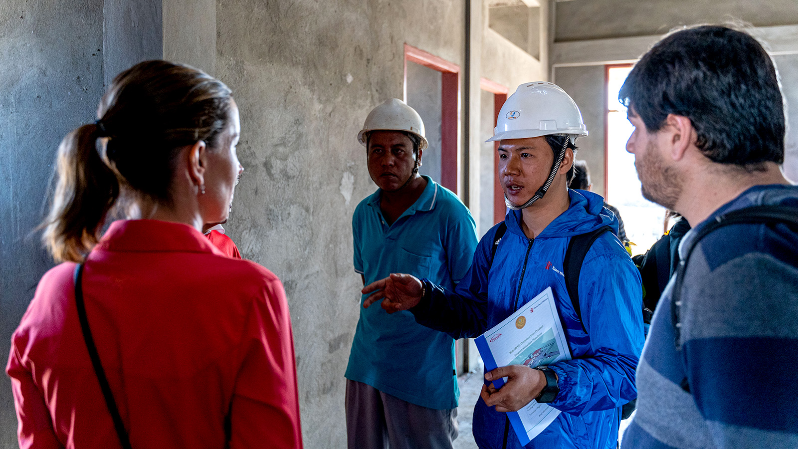 five people having a discussion in a construction building